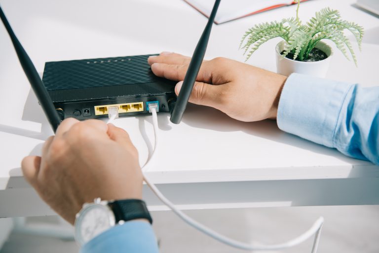 partial view of businessman plugging router on office desk