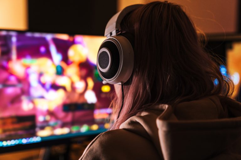 Image from back of girl playing video game on personal computer