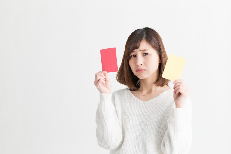 赤と黄色のカードを持った女性